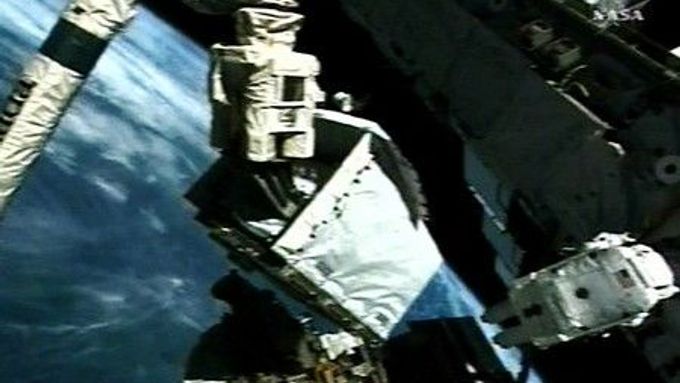 Astronauti Mike Fossum (vpravo) čeká až se modul (vlevo) přesune na externí plošinu 2.