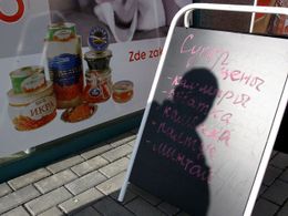 Rusky psaná cedule a česká reklama na kaviár před obchodem Kalinka ve "Žlutých domech" na pražské Hůrce