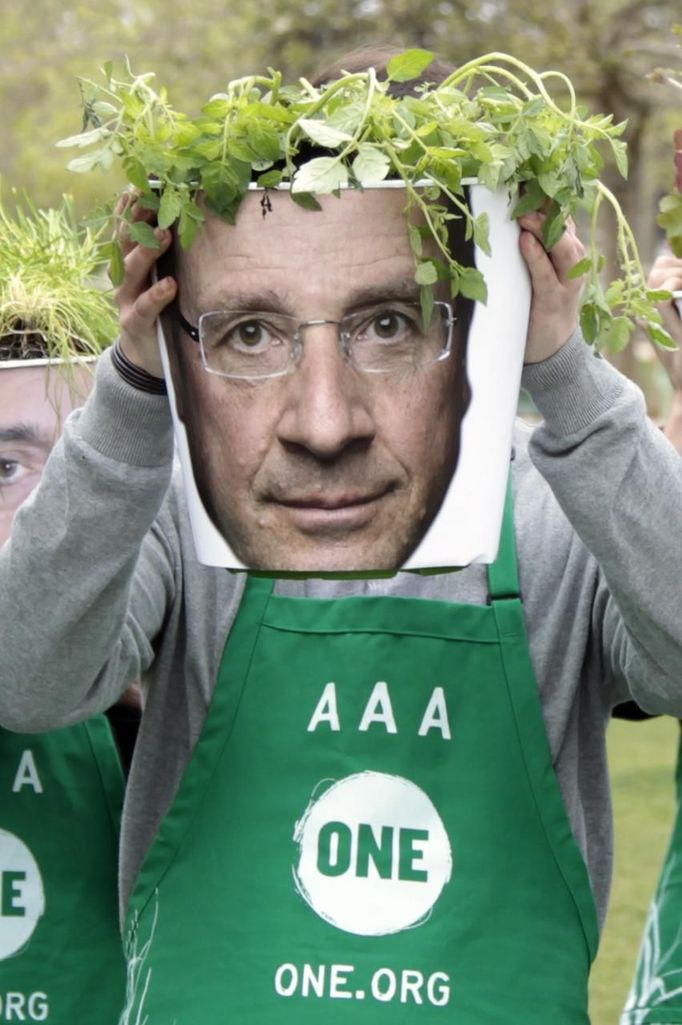 A member of the NGO organization "ONE" holds plants in a pot with a picture of Hollande, Socialist Party candidate for the 2012 French presidential election, in front of the Eiffel tower in Paris