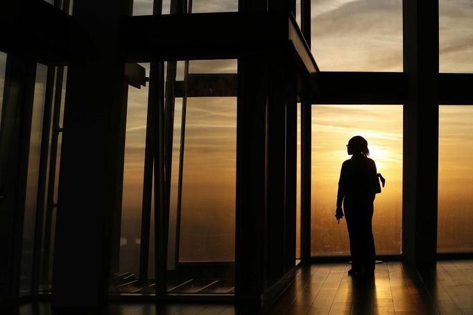 ATTENTION EDITORS - EMBARGOED FOR PUBLICATION TO 00:01 GMT JANUARY 11, 2013 An employee poses during sunrise as she looks out the window from The View gallery at the Shard, western Europe's tallest building, in London January 8, 2013. The View, the public viewing deck accessible by high speed elevators on the 309 metre (1013 feet) Shard building, opens on February 1. Picture taken January 8, 2013. REUTERS/Stefan Wermuth (BRITAIN - Tags: TRAVEL CITYSCAPE) TEMPLATE OUT Published: Led. 10, 2013, 12:06 odp.