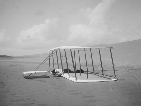 Wilbur Wright testuje ideální letovou polohu ve stroji Kitty Hawk. Na snímku ještě  coby bezmotorový kluzák.
