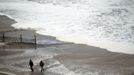 People walk near a surf from Hurricane Sandy rising past sand fences onto the beach in Ocean City, Maryland October 28, 2012. Tens of millions of East Coast residents scrambled on Sunday to prepare for Hurricane Sandy, which could make landfall as the largest storm to hit the United States, bringing battering winds, flooding and even heavy snow. REUTERS/Kevin Lamarque (UNITED STATES - Tags: ENVIRONMENT DISASTER)