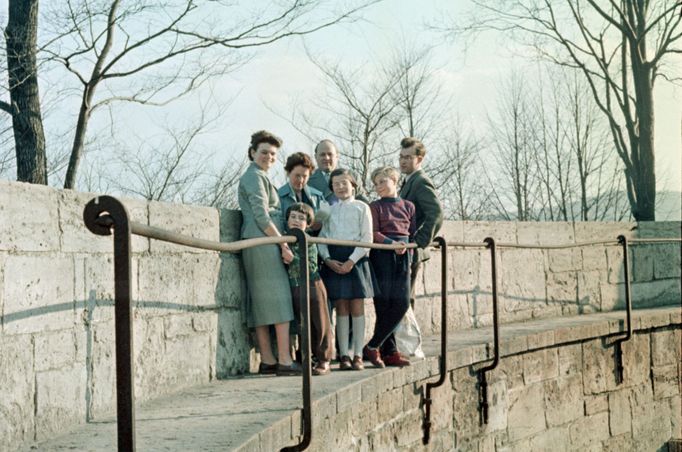 Skupina lidí pózuje na kamenné zídce v zimním období. Fotografie zachycuje rodinu v dobovém oblečení, pravděpodobně v 50. letech 20. století v NDR.