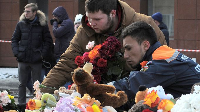 Lidé pokládají květiny a hračky k obchodnímu centru ve městě Kemerovo, kde požár zabil desítky lidí včetně dětí.