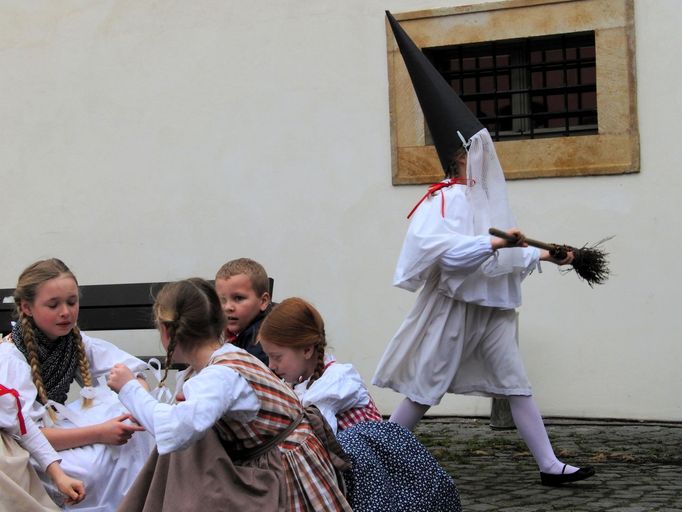 Ambrož měl na hlavě černou, do špičky stočenou čapku se závojem přes obličej. Rozhazoval kolem kostela sladkosti a honil děti, které si přišly zamlsat.