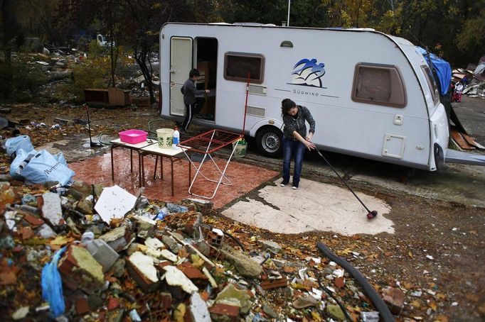 Saray Armendia uses a broom to sweep outside her caravan after a bulldozer demolished the former school, where her in-laws lived at, at the Spanish gypsy settlement of Puerta de Hierro, in the outskirts of Madrid November 20, 2012. Fifty-four families have been living in Puerta de Hierro, on the banks of the Manzanares river for over 50 years. Since the summer of 2010, the community has been subject to evictions on the grounds that the dwellings are illegal. Families, whose homes have been demolished, move in with relatives whose houses still remain while the debris keeps piling up around them as more demolitions take place. REUTERS/Susana Vera (SPAIN - Tags: CIVIL UNREST BUSINESS CONSTRUCTION) Published: Lis. 20, 2012, 4:50 odp.