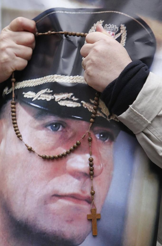 REFILE - ADDING "BEADS" TO FIRST SENTENCE OF CAPTION A man holds rosary beads together with a picture of Ante Gotovina while people celebrate after an appeals court overturned the convictions of Gotovina and Mladen Markac, at the main square in Zagreb November 16, 2012. Gotovina, who was a commander in the Split district of the Croatian army, and Markac, who was a Croatian police commander, had been convicted of crimes against humanity and war crimes during the wars that followed the break-up of Yugoslavia. Judges ordered the pair's immediate release. REUTERS/Antonio Bronic (CROATIA - Tags: SOCIETY POLITICS) Published: Lis. 16, 2012, 10:07 dop.