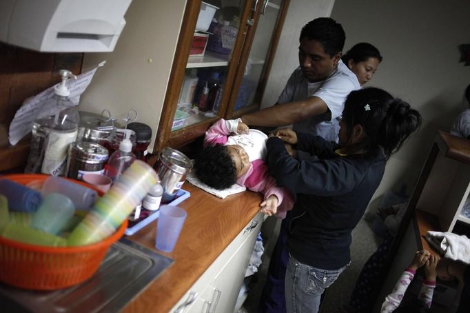 Nurses help a child in the San Jose Hospice, in Sacatepequez, 45 km (28 miles) of Guatemala City, November 30, 2012. About 68 HIV-infected children receive free medical care at the hospice, many of them were found abandoned in markets, churches, fire stations, left neglected in hospitals or in some instances, brought in by their families who cannot afford to pay for their medical treatment. World AIDS Day which falls on December 1 is commemorated across the world to raise awareness of the pandemic. REUTERS/Jorge Dan Lopez (GUATEMALA - Tags: ANNIVERSARY HEALTH) Published: Pro. 1, 2012, 1:51 dop.