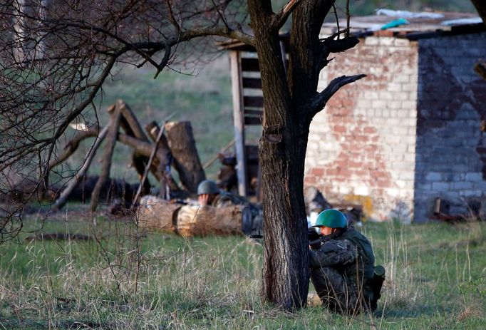 An Ukrainian soldier aim his rifle and takes cover behind a tree as pro-Russia protesters gathered in front of a Ukrainian airbase in Kramatorsk, 15. 4. 2014