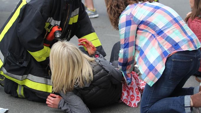 Zraněná žena leží na chodníku po bombovém útoku na cíl běhu.