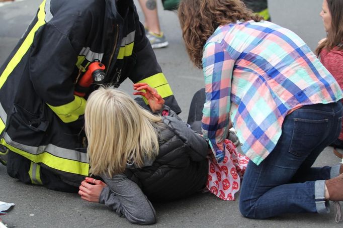 Zraněná žena leží na chodníku po bombovém útoku na cíl běhu.