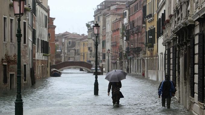 People walk in a flooded street during a period of seasonal high water in Venice November 11, 2012. The water level in the canal city rose to 149 cm (59 inches) above nor