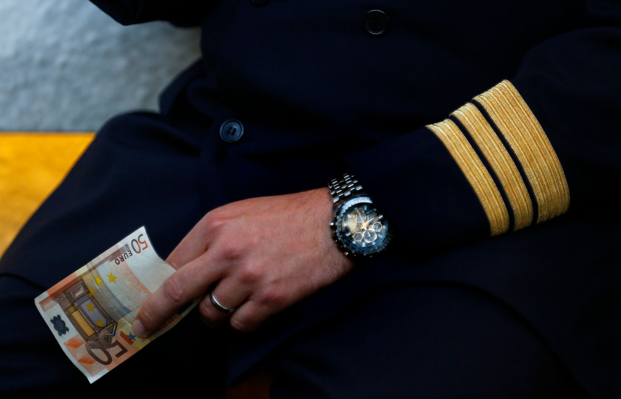 A pilot of German air carrier Lufthansa holds a 50 euro bank note as he waits for his bill in a coffee bar at the Fraport airport in Frankfurt