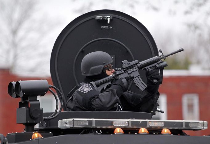 Člen jednotky SWAT míří z obrněného transportéru na okolní budovy při pátrání po osobě podezřelé ze spáchání teroristického útoku na bostonském maratonu.