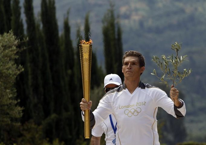 Spyridon Gianniotis, Greece's world champion of swimming, runs with the Olympic flame and an olive branch during the Olympic torch relay at the site of ancient Olympia in Greece May 10, 2012. REUTERS/John Kolesidis (GREECE - Tags: SPORT OLYMPICS) Published: Kvě. 10, 2012, 10:30 dop.