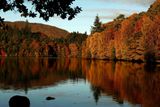 Barevné listí na stromech se odráží na hladině jezera Faskally ve Skotsku.