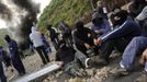 Coal miners wait as smoke billows from a barricade of burning tyres during a protest against government spending cuts in the mining sector, along National Highway 630 in Cinera, northern Spanish province of Leon June 11, 2012. REUTERS/Eloy Alonso (SPAIN - Tags: CIVIL UNREST BUSINESS EMPLOYMENT ENERGY) Published: Čer. 11, 2012, 3:42 odp.