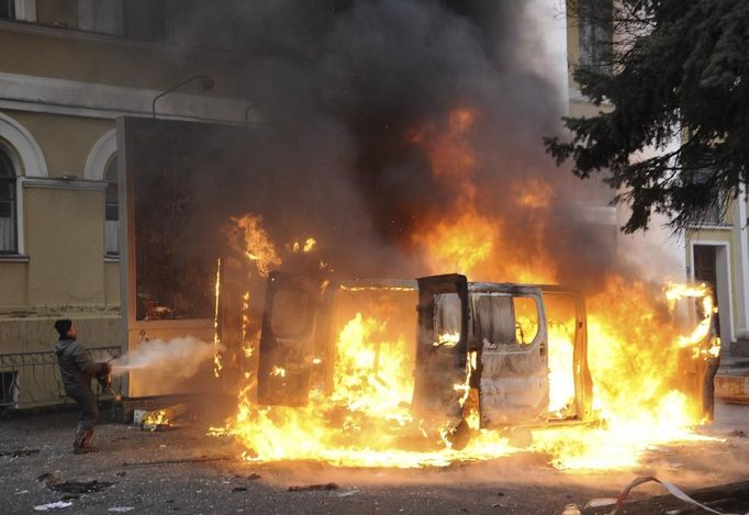 A man attempts to extinguish a burning vehicle during clashes with riot police near Independence Square in Kiev February 20, 2014. Ukrainian protesters hurling petrol bom