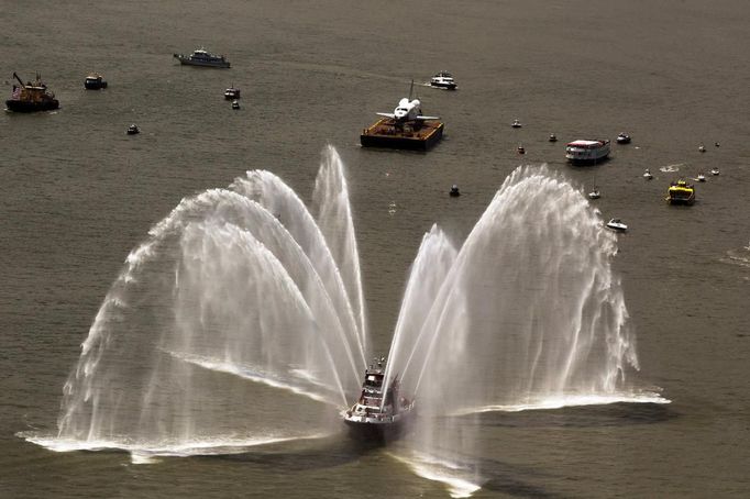 Fire boats spray water in front of the Space Shuttle Enterprise as it floats up the Hudson River June 6, 2012, as it rides past the New York skyline on a barge to be placed at the Intrepid Sea, Air and Space Museum. REUTERS/Lucas Jackson (UNITED STATES - Tags: SCIENCE TECHNOLOGY TRANSPORT) Published: Čer. 6, 2012, 5:09 odp.