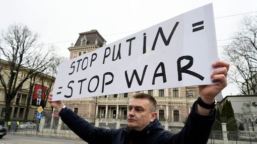 Podporovatel zesnulého ruského opozičníka Alexeje Navalného před ruskou ambasádou v lotyšské Rize drží transparent hlásající "stop Putinovi = stop válce".