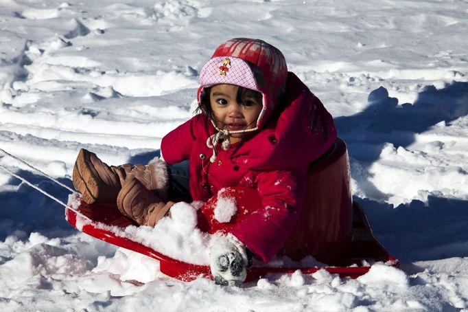 A child is pulled by her parents during a ride down a hill on toboggan after a winter storm in Jersey City, New Jersey, February 9, 2013. A blizzard packing hurricane-force winds pummelled the northeastern United States on Saturday, killing at least one person, leaving about 600,000 customers without power and disrupting thousands of flights. REUTERS/Eduardo Munoz (UNITED STATES - Tags: ENVIRONMENT DISASTER) Published: Úno. 10, 2013, 12:35 dop.