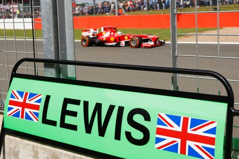 Ferrari Formula One driver Alonso drives past pit board of M