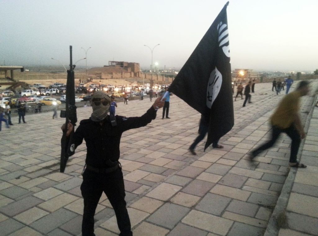 Ozbrojenec s vlajkou ISIL v Mosulu.