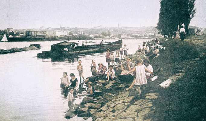 Kolorovaný dobový snímek zachycující rekreaci u vody v Československu.