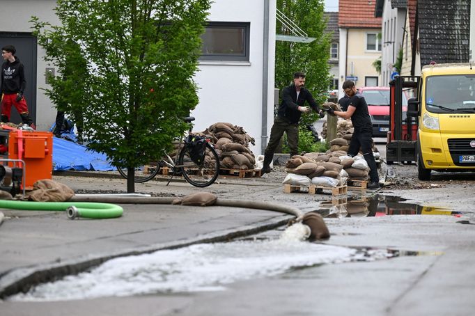 Lidé pracují na úklidu silnice po silných záplavách v Reichertshofenu u Ingolstadtu v Německu.