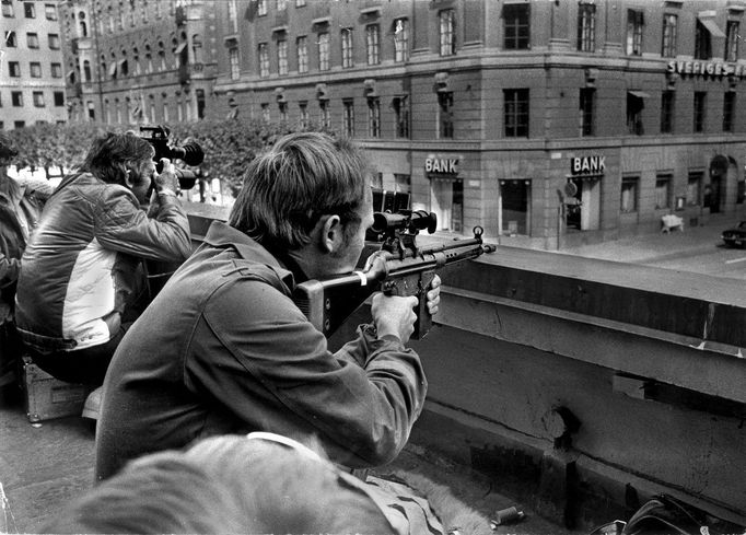 Fotografové a policejní odstřelovači leží vedle sebe na střeše naproti bance Kreditbanken na náměstí Norrmalmstorg ve Stockholmu 24. srpna 1973.