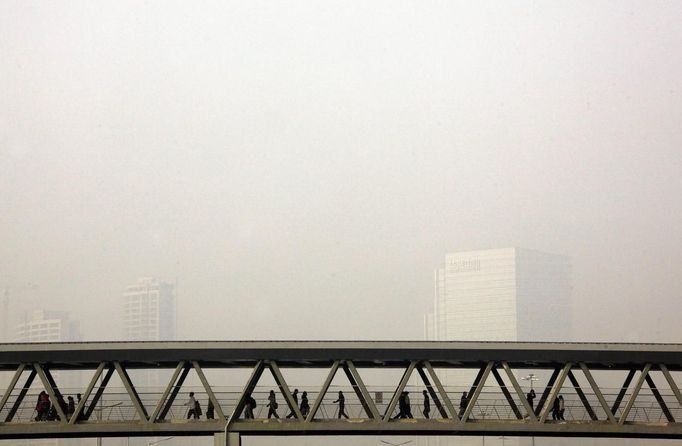 Buildings shrouded in haze behind pedestrians walking across a bridge above a main road in central Beijing October 27, 2012. China's heavily polluted capital plans to reduce air pollution levels by 15 percent by 2015 and 30 percent by 2020 through phasing out old cars, relocating factories and planting new forests, state media reported earlier this year. REUTERS/David Gray (CHINA - Tags: SOCIETY ENVIRONMENT) Published: Říj. 27, 2012, 4:10 dop.