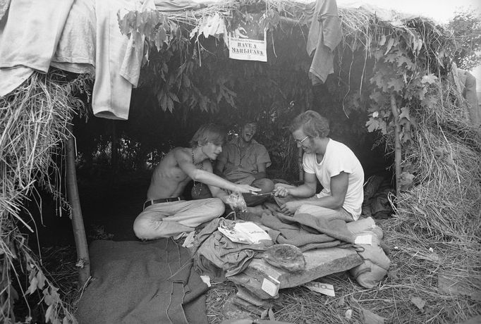 Na snímku z Woodstocku v roce 1969 účastníci festivalu hledají přístřeší ve slaměné chýši s nápisem "Dejte si trávu".
