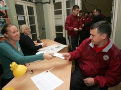 Volili také fotbalisté. Trenér Jurijs Andrejevs dostává volební lístek od členky komise v Rize.