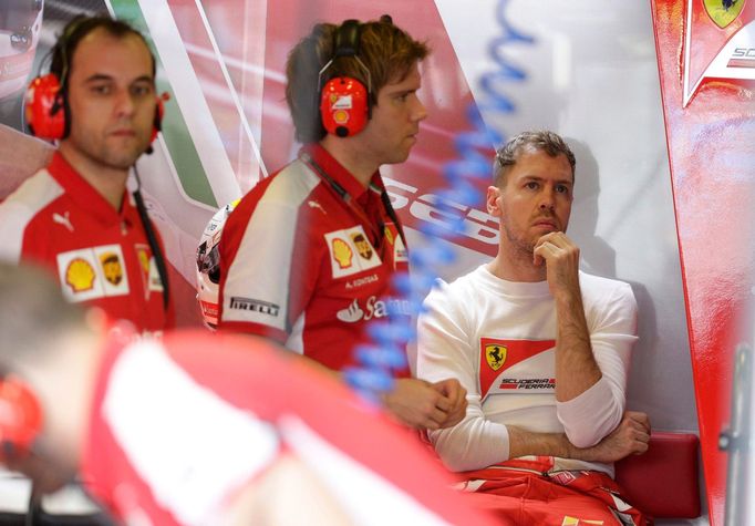 Ferrari Formula One driver Sebastian Vettel of Germany (R) reacts in the team garage during the third practice session of the Australian F1 Grand Prix at the Albert Park