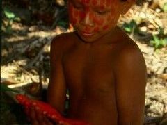 Holčička z kmene Suruwaha si prohlíží ruce pomalované červenou barvou