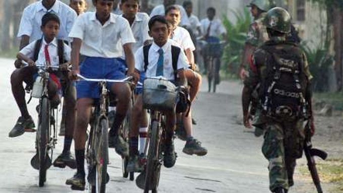 Děti jedou do školy po silnici hlídané vojáky. Srí Lanka jedná v Ženevě o své budoucnosti.