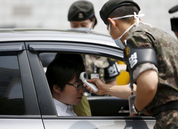 Jihokorejští vojáci u vstupu na ministerstvo obrany kontrolují tělesnou teplotu návštěvníků.