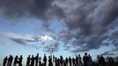 People stand on a hillside behind a memorial for victims behind the theater where a gunman opened fire on moviegoers in Aurora, Colorado July 22, 2012. Residents of a Denver suburb mourned their dead on Sunday from a shooting rampage by a "demonic" gunman who killed 12 people and wounded 58 after opening fire at a cinema showing the new Batman movie. REUTERS/Shannon Stapleton (UNITED STATES - Tags: DISASTER SOCIETY CIVIL UNREST CRIME LAW) Published: Čec. 23, 2012, 2:32 dop.