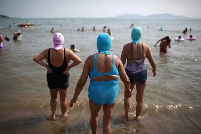 Women, wearing nylon masks, walk towards the sea during their visit to a beach in Qingdao, Shandong province July 6, 2012. The mask, which was invented by a woman about seven years ago, is used to block the sun's rays. The mask is under mass production and is on sale at local swimwear stores. REUTERS/Aly Song (CHINA - Tags: SOCIETY ENVIRONMENT TRAVEL) Published: Čec. 6, 2012, 4:10 odp.