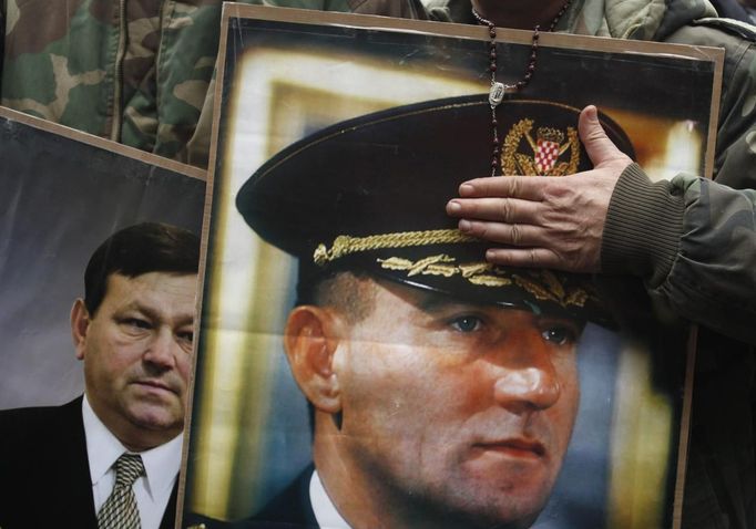 A man touches the picture of Ante Gotovina as the picture of Mladen Markac is seen beside while people celebrate after an appeals court overturned the convictions of Gotovina and Markac, at the main square in Zagreb November 16, 2012. Gotovina, who was a commander in the Split district of the Croatian army, and Markac, who was a Croatian police commander, had been convicted of crimes against humanity and war crimes during the wars that followed the break-up of Yugoslavia. Judges ordered the pair's immediate release. REUTERS/Antonio Bronic (CROATIA - Tags: SOCIETY POLITICS) Published: Lis. 16, 2012, 10 dop.