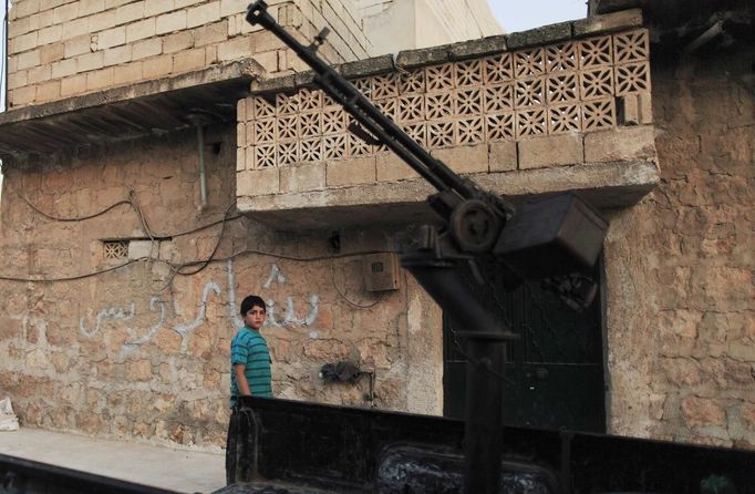 A boy walks past an anti-aircraft machine gun belonging to Free Syrian Army members in Attarib, on the outskirts of Aleppo province July 30, 2012. The graffiti on the wall reads: "Bashar only". REUTERS/Zohra Bensemra (SYRIA - Tags: POLITICS CONFLICT CIVIL UNREST) Published: Čec. 30, 2012, 7:24 odp.