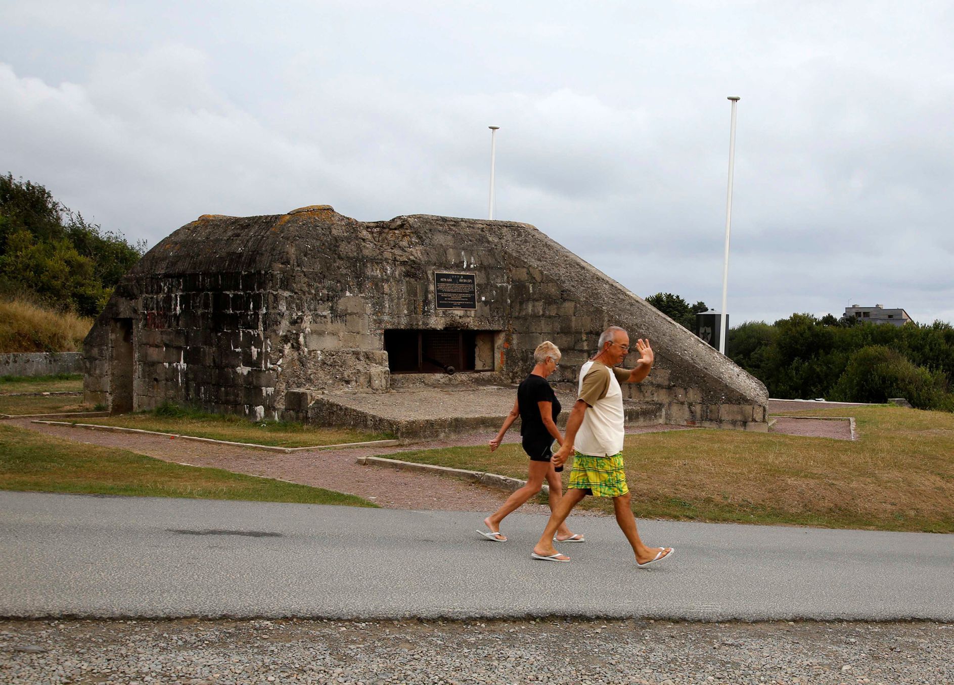 Tourists walk past a former German bunker overlooking the D-Day landing zone on Omaha Beach near Saint Laurent sur Mer