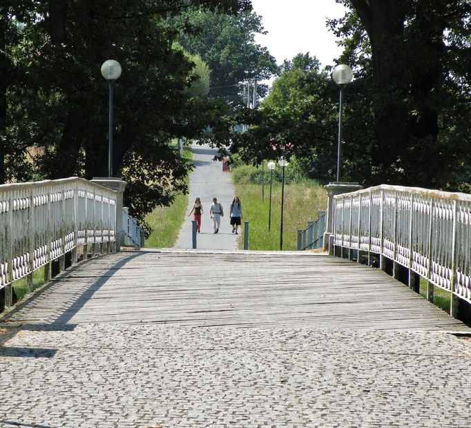 Fotografie Pohled na příchozí cestu k parku zobrazuje několik lidí, kteří s ejdou v horku podívat do areálu parku a zámku.