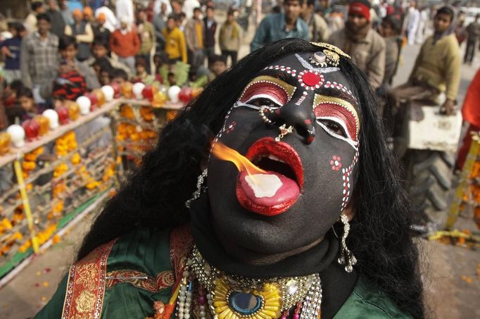 A man dressed as Hindu goddess Kali, the goddess of power, performs with a burning camphor tablet on his tongue during a religious procession ahead of the "Kumbh Mela", or Pitcher Festival, in the northern Indian city of Allahabad January 6, 2013. During the festival, hundreds of thousands of Hindus take part in a religious gathering at the banks of the river Ganges. The festival is held every 12 years in different Indian cities. REUTERS/Jitendra Prakash (INDIA - Tags: RELIGION ANNIVERSARY TPX IMAGES OF THE DAY) Published: Led. 6, 2013, 11:39 dop.