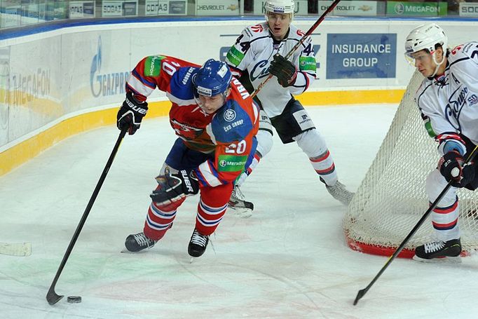 Hokejista Lva Praha Petr Vrána s pukem proti Artursi Kuldovi (vlevo) v utkání KHL 2012/13 proti Novosibirsku.