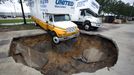 A truck hangs over the edge of a sinkhole that opened up in the parking lot of Hughes Relocation Services, Monday, June 25, 2012, in Salt Springs, Fla. Tropical Storm Debby raked the Tampa Bay area with high wind and heavy rain Monday in a drenching that could top 2 feet over the next few days and trigger widespread flooding. (AP Photo/The Ocala Star-Banner, Alan Youngblood)