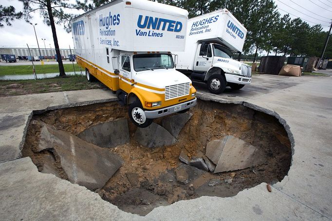 A truck hangs over the edge of a sinkhole that opened up in the parking lot of Hughes Relocation Services, Monday, June 25, 2012, in Salt Springs, Fla. Tropical Storm Debby raked the Tampa Bay area with high wind and heavy rain Monday in a drenching that could top 2 feet over the next few days and trigger widespread flooding. (AP Photo/The Ocala Star-Banner, Alan Youngblood)