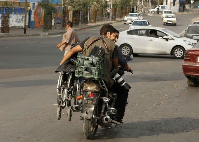 Wheelchair-bound Palestinian freelance photographer Moamen Qreiqea holds his wheelchair as he rides on a motorcycle on a street in Gaza City October 1, 2012. Qreiqea, 25, lost both his legs in an Israeli air strike in 2008 while taking pictures east of Gaza. The father of two is determined to continue his career despite his disability. REUTERS/Suhaib Salem (GAZA - Tags: SOCIETY MEDIA) Published: Říj. 1, 2012, 3:39 odp.