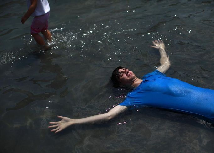 A man lies in the fountain at Washington Square Park in New York July 1, 2012. Blistering heat blanketed much of the eastern United States for the third straight day on Sunday, after violent storms that took at least a dozen lives and knocked out power to more than 3 million customers. REUTERS/Eric Thayer (UNITED STATES - Tags: ENVIRONMENT SOCIETY) Published: Čec. 1, 2012, 8:43 odp.