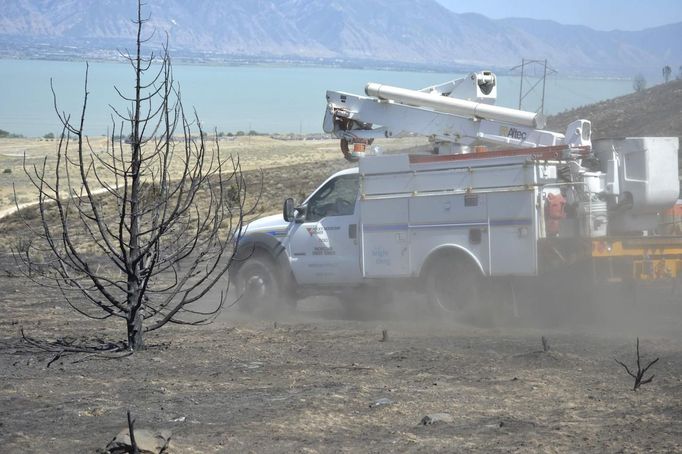 Power crews work to repair power lines damaged from the so-called Dump Fire near Eagle Mountain, Utah, June 23, 2012. A raging Utah brush fire ignited by target shooting in dry grass has forced some 8,000 people from their homes in two small communities since June 22 as high winds fanned flames toward a nearby explosives factory, authorities said. REUTERS/Jeff McGrath (UNITED STATES - Tags: ENVIRONMENT DISASTER) Published: Čer. 24, 2012, 2:31 dop.